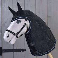 Plyšová konská hlava na drevenej tyči s pláštenkou Hobby Horse LarDen Pláštenka Silver Stone s krytmi na uši a ohlávkou, stojaca pred drevenými panelovými dverami.