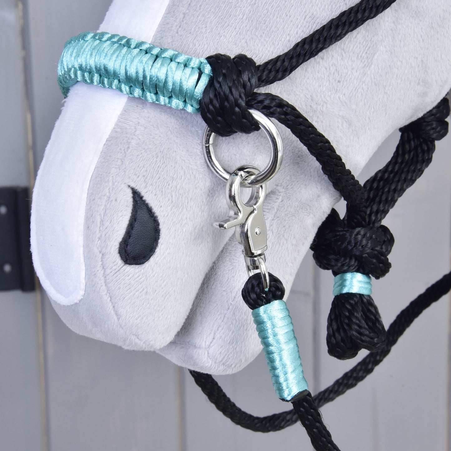 Detail sivej hlavy Hobby Horse s ohlávkou z Povrazového setu Turquoise od Hobby Horse LarDen a ladiacimi oprátami s kovovým krúžkom a karabínou, na svetlosivom drevenom pozadí.