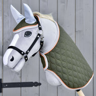 Set Moos od Hobby Horse LarDen so sivým Hobby Horse na drevenej tyči, čiernou uzdečkou, zelenou prešívanou dekou a svetlomodrou čabrakou na sivej drevenej stene.