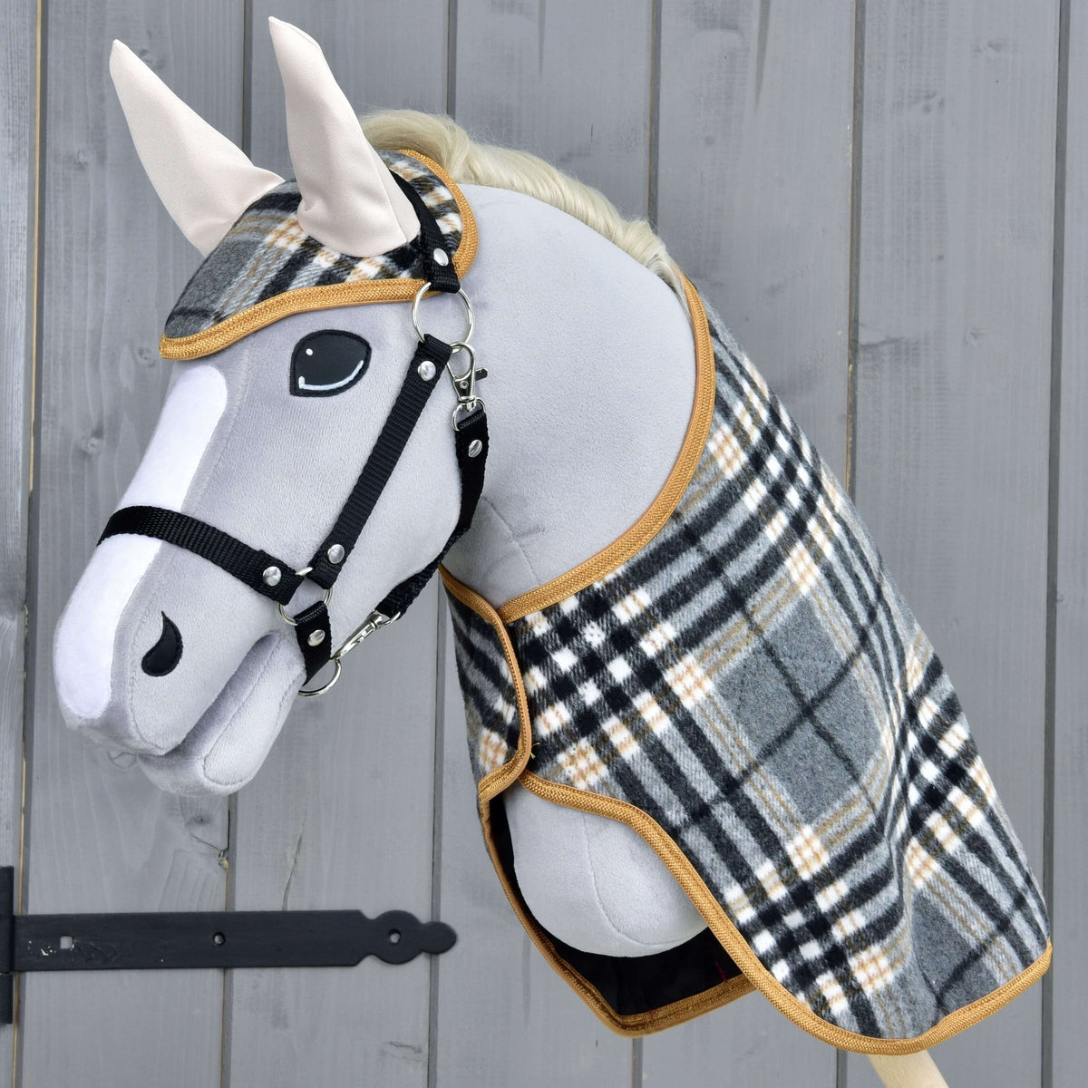 Hobby Horse LarDen Set England Grey so sivým plyšovým Hobby Horse, čiernou uzdečkou a opratami, károvanou dekou a ladiacou čabrakou, vytvárajúci pôvabnú dekoráciu na drevenom pozadí.