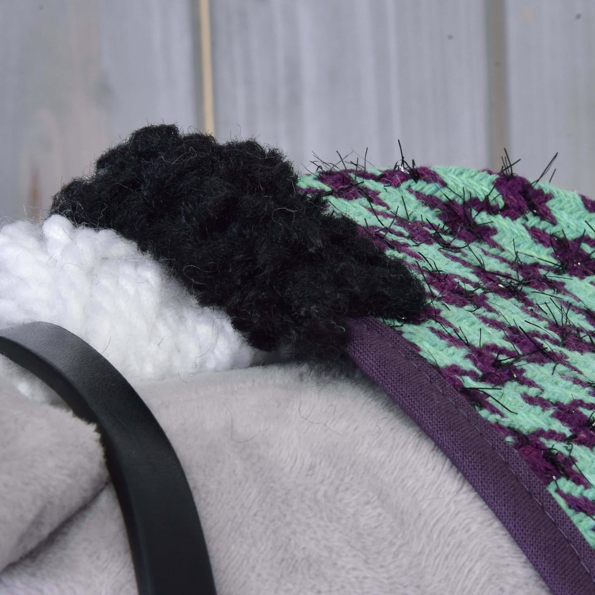 Detail hlavy Set Harmony Green od Hobby Horse LarDen, zobrazujúci čierno-bielu priadzovú hrivu, zelenú a fialovú textúrovanú látku, sivý plyšový povrch a čierny remienok ohlávky na drevenom pozadí.