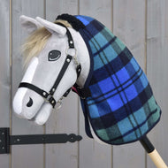 Hobby Horse LarDen s šedou látkovou hlavou, černou uzdečkou, světlou hřívou, malovaným okem a nozdrami, na sobě má deku Deka stájová Perth v modro-zeleném kostkovaném vzoru. Stojí před dřevěným pozadím.