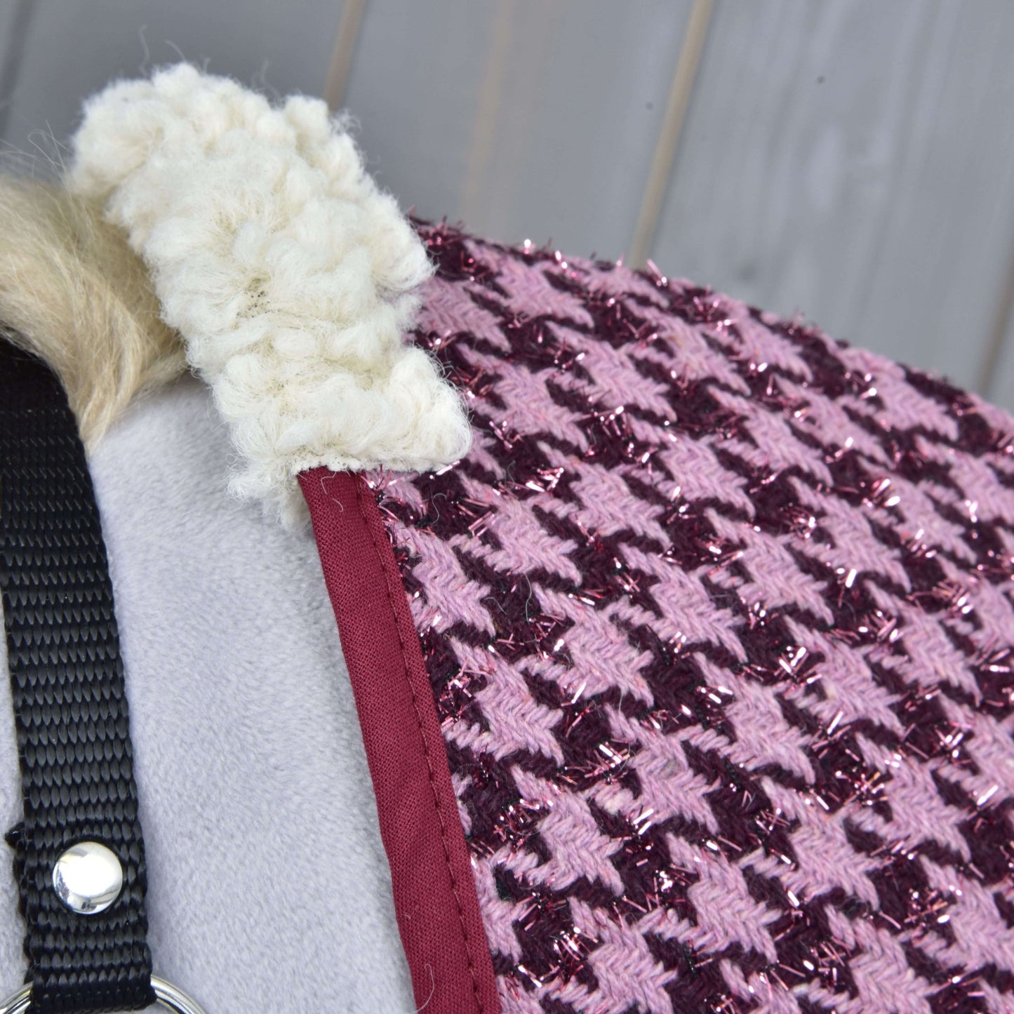 Deka stajňová Winter Magic od Hobby Horse LarDen, detail textúrovaného ružového a fialového vzoru kohútej stopy s trblietavými vláknami, červeným lemovaním, nadýchaným bielym golierom a materiálom PES, prehodená cez sivý podklad s čiernym popruhom a kovovým krúžkom.