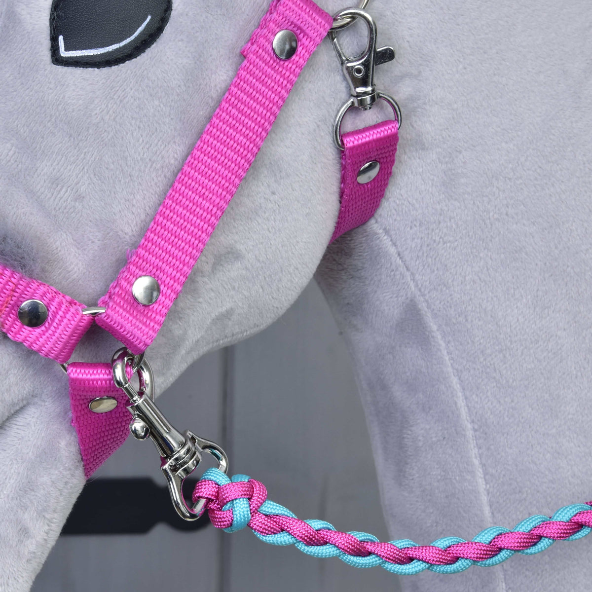 Detailný záber na sivého plyšového koňa so Set Perfect Combination Pink od Hobby Horse LarDen – ružová ohlávka s kožušinovým polstrovaním s pleteným modro-ružovým vodidlom, pripevneným striebornou karabínou – ideálny pre fanúšikov doplnkov pre Hobby Horse.