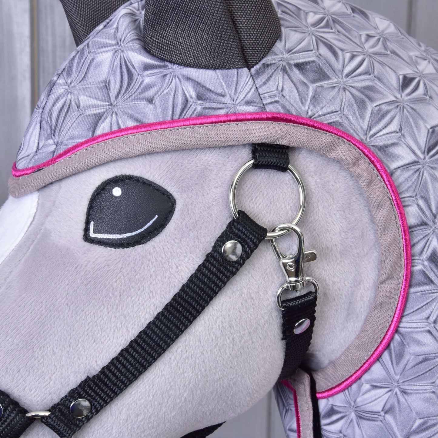 Detail Hobby Horse LarDen Pláštěnka Valentine, plyšové koňské hlavy s šedou látkou s geometrickým vzorem, černou uzdečkou a růžovým lemováním, s kovovou kroužkovou sponou – doplněk do každého počasí pro stylovou ochranu.