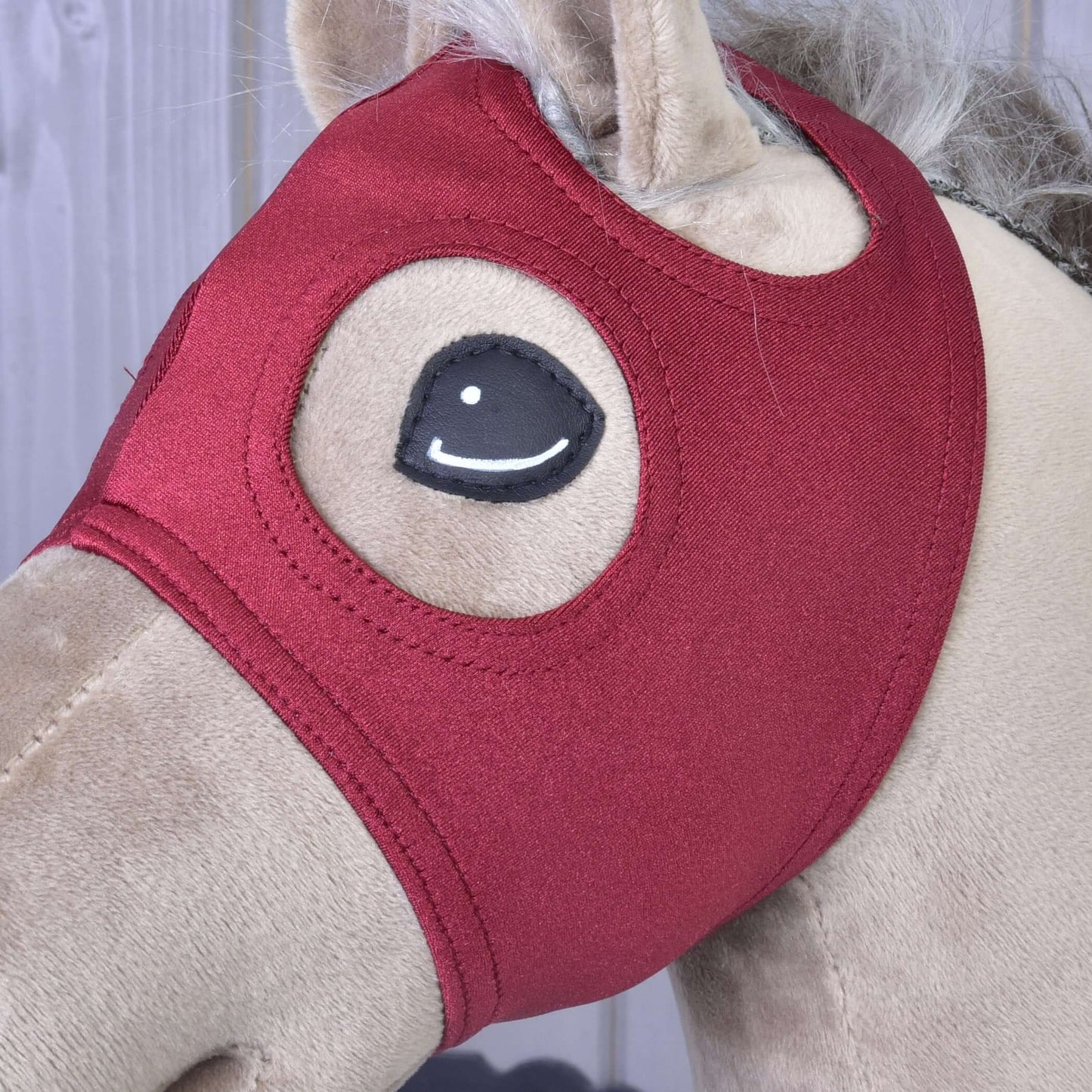 Detail béžového Hobby Horse od Hobby Horse LarDen s červenou sametovou Maskou bez uší Velvet zakrývající hlavu, s vyšitýma očima a viditelnou huňatou hřívou.