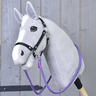Hobby Horse LarDen „Otěže Viola“, šedý Hobby Horse s bílou lysinou, černou uzdečkou a výraznými ručně vyráběnými otěžemi, s plyšovou hlavou na pevné tyči, zobrazený před světlým dřevěným plotem.
