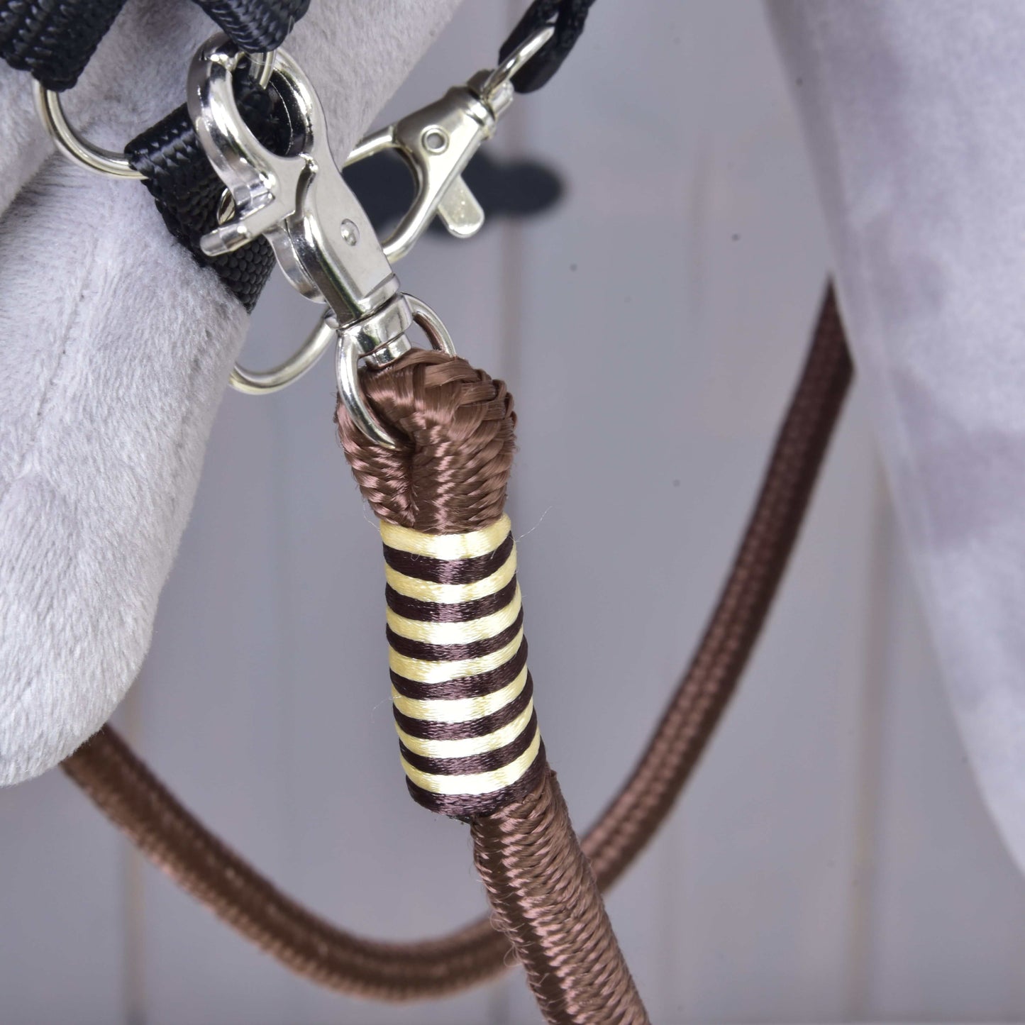 Detail kovovej karabíny pripevňujúcej hnedé polypropylénové lano so zlatým a čiernym ozdobným omotaním k sivej látke, súčasť Oprát Vivaldi od Hobby Horse LarDen.