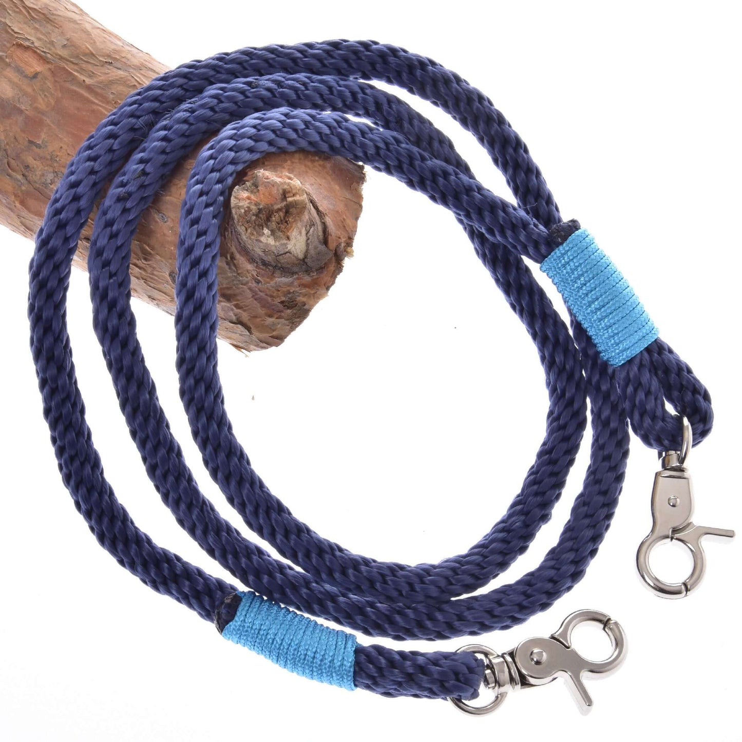 Provazový set Dark Blue od Hobby Horse LarDen obsahuje stočené tmavě modré vodítko s kovovými karabinami na obou koncích, každou omotanou jasně modrou nití, a je vystavené na světle hnědé dřevěné větvi – stylový jezdecký doplněk.