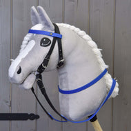 Plyšový Hobby Horse od Hobby Horse LarDen se šedým obličejem, bílou hřívou a modrými pogumovanými otěžemi, nasazený na dřevěné tyči před dřevěným panelovým pozadím.