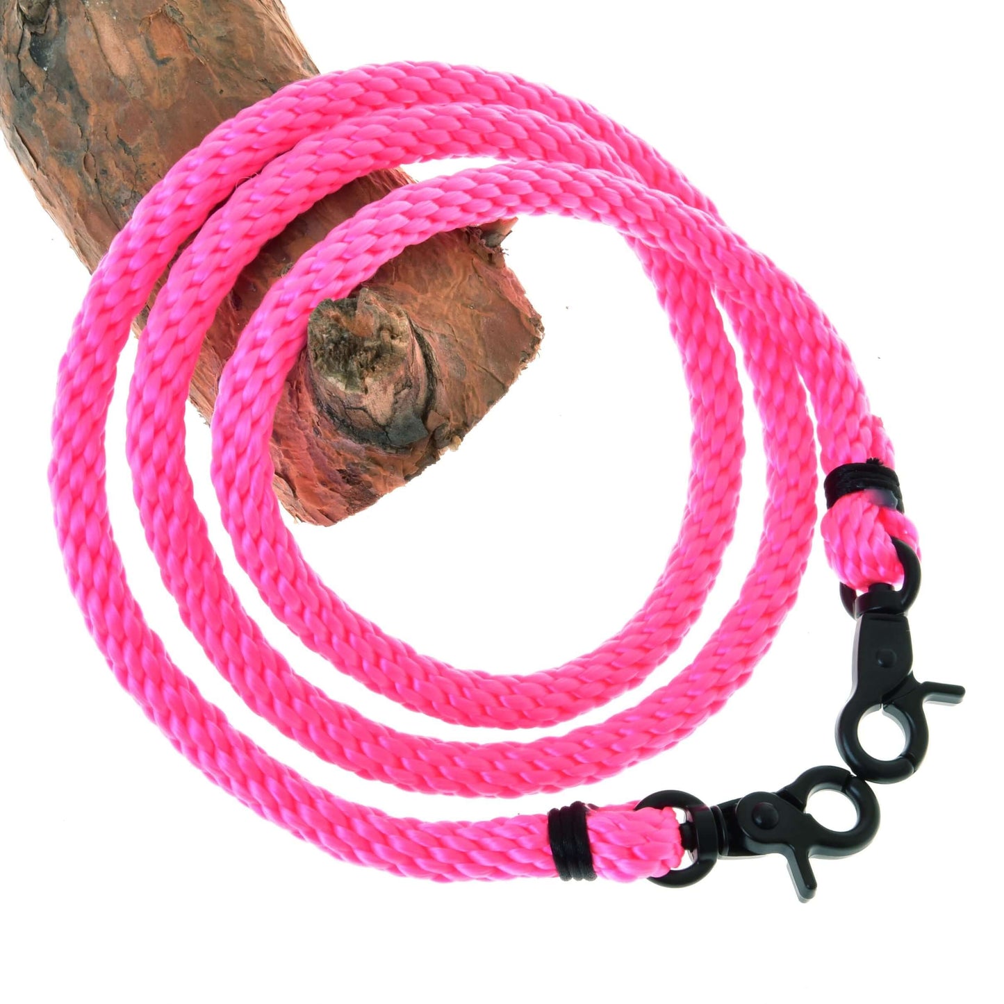 Opraty Pink od Hobby Horse LarDen, žiarivo ružové pletené lano s čiernymi kovovými karabínami na oboch koncoch, stočené na vetve stromu, ideálne ako opraty pre Hobby Horse.